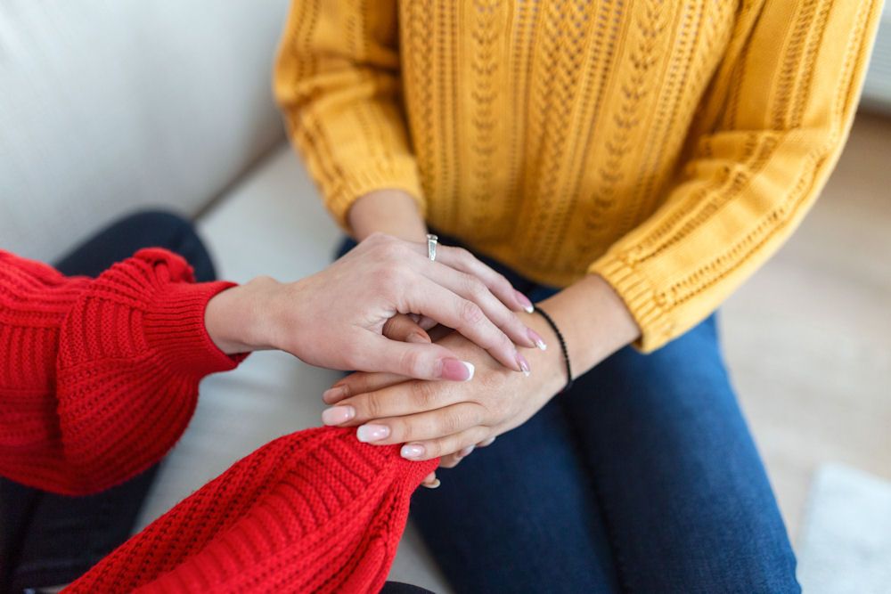 two women sitting together on a couch offering support in mental health therapy program