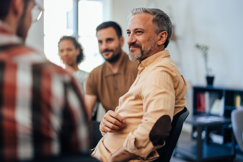 A mature man carefully listened while others spoke during the group therapy.